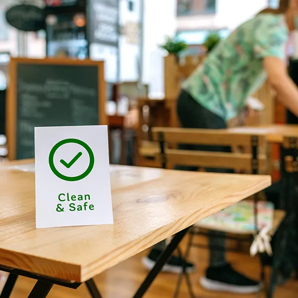 Skylt med texten Clean & Safe på ett cafébord
